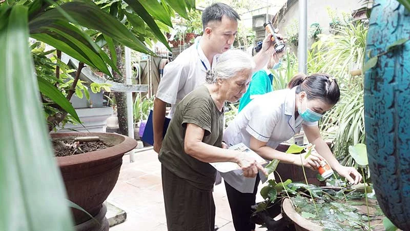 Cán bộ y tế hướng dẫn người dân trên địa bàn quận Long Biên kiểm tra và diệt bọ gậy. (Ảnh DUY TUÂN)