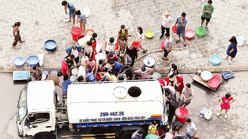 Người dân Khu đô thị Thanh Hà xếp hàng lấy nước sạch từ xe téc. (Ảnh SƠN BÁCH)