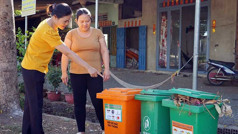 Cán bộ Hội Liên hiệp Phụ nữ xã Lang Minh, huyện Xuân Lộc, tỉnh Đồng Nai hướng dẫn người dân phân loại rác tại nguồn. (Ảnh MẠNH THÌN)