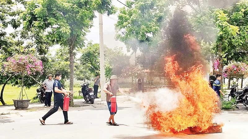 Người dân xã Yên Mỹ, huyện Thanh Trì thực hành sử dụng bình chữa cháy để dập lửa. (Ảnh NGUYỄN QUÂN)