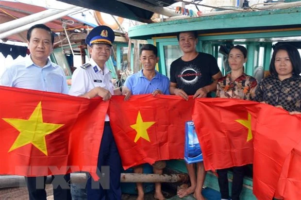 Tặng cờ Tổ quốc cho bà con ngư dân huyện Cát Hải. (Ảnh: TTXVN)