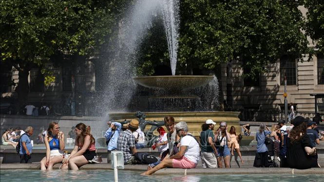 Người dân tránh nóng bên đài phun nước tại Quảng trường Trafalgar ở thủ đô London, Anh, ngày 17/6/2022. (Ảnh: AFP/TTXVN)