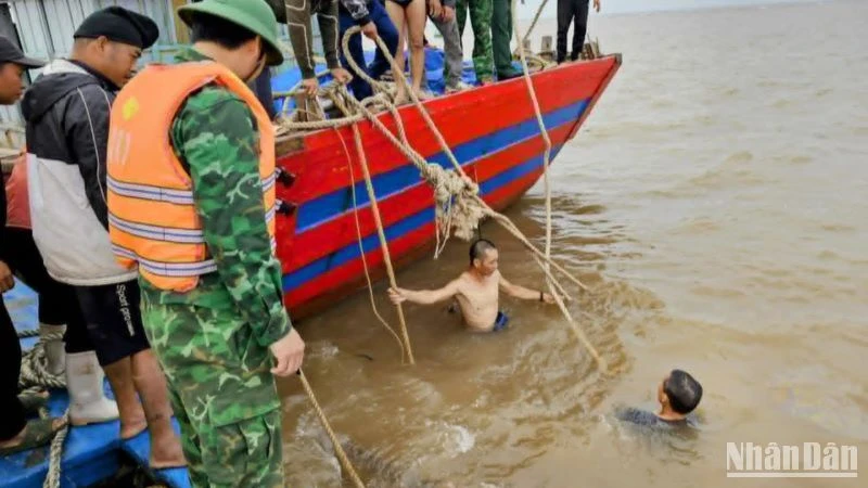 Huy động thợ lặn xuống nước buộc dây để lai dắt tàu cá bị chìm vào bờ.