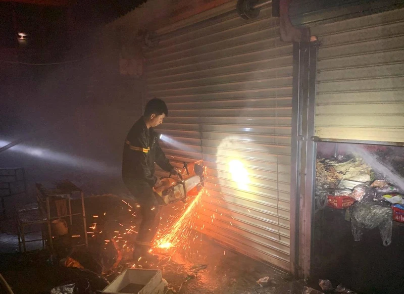 Lực lượng chức năng phải dùng cưa cưa cửa cuốn các ki-ốt trong chợ thị xã Buôn Hồ chữa cháy.