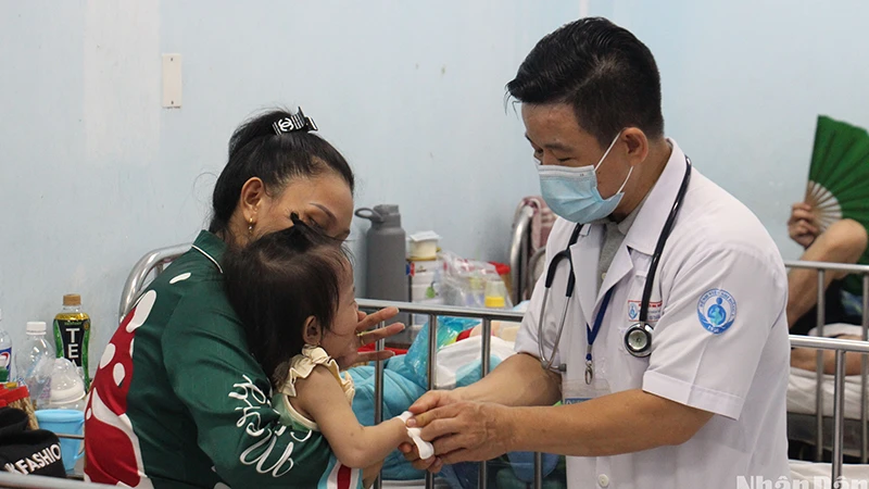 Bác sĩ Bệnh viện Nhi đồng 1 đang khám cho trẻ mắc tay chân miệng (Ảnh: Thế Anh)