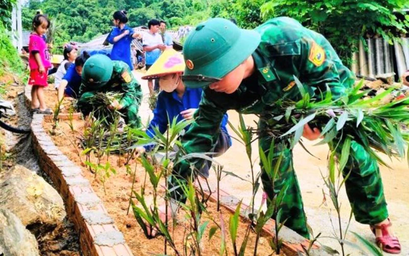 Thanh niên cùng lực lượng vũ trang trồng hoa bên đường nội bản Con Dao, xã Quang Chiểu.