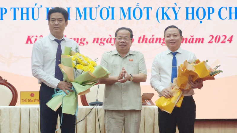 Chủ tịch Hội đồng nhân dân tỉnh Kiên Giang Mai Văn Huỳnh tặng hoa chúc mừng ông Lê Quốc Anh (bìa trái) và ông Lê Hữu Toàn (bìa phải).