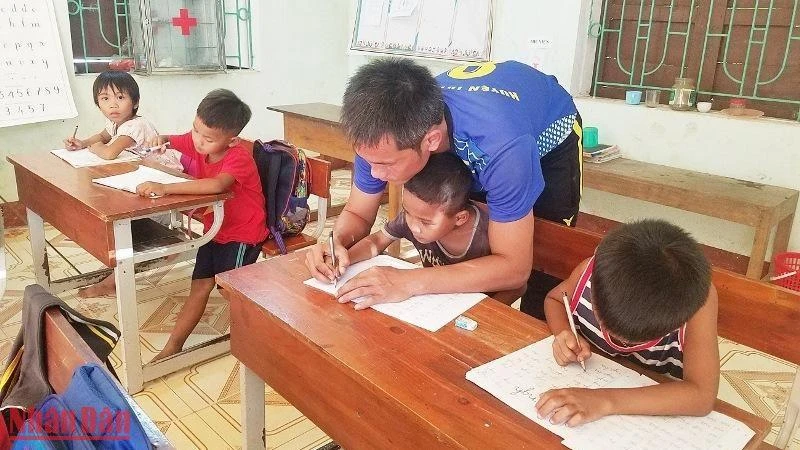 Thầy giáo dạy học sinh đồng bào Mã Liềng ở huyện Tuyên Hóa (Quảng Bình) viết chữ.