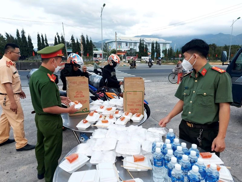 Cán bộ, chiến sĩ chuẩn bị phần ăn và nhiệt tình tiếp sức cho người đi xe gắn máy từ các tỉnh phía nam về các tỉnh miền trung vui Tết khi ngang qua điểm hỗ trợ tại huyện Thuận Bắc, tỉnh Ninh Thuận. 