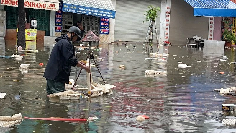 Nhân viên Công ty TNHH MTV Công trình đô thị Nam Định vớt rác trôi nổi, tiêu thoát nước úng ngập trên đường Trần Hưng Đạo, thành phố Nam Định.