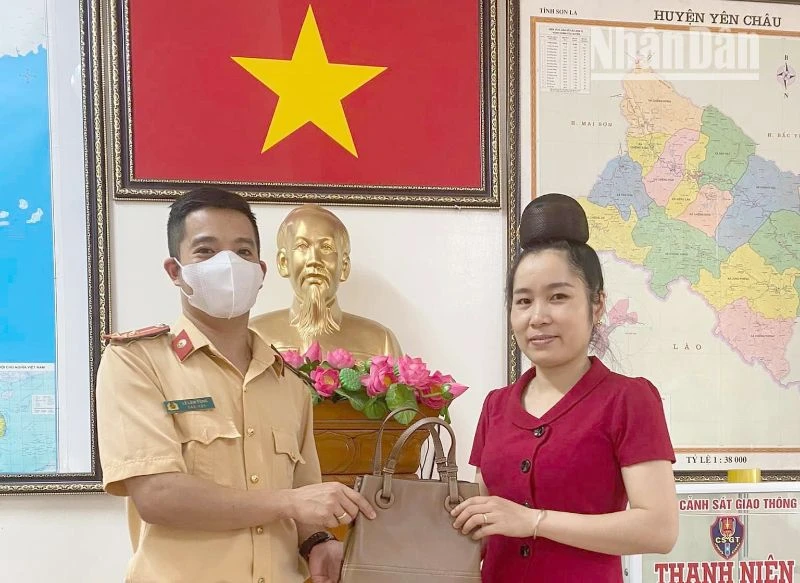 Thượng úy Lê Lâm Tùng trả lại chiếc túi xách cho chị Lường Thị Giang.
