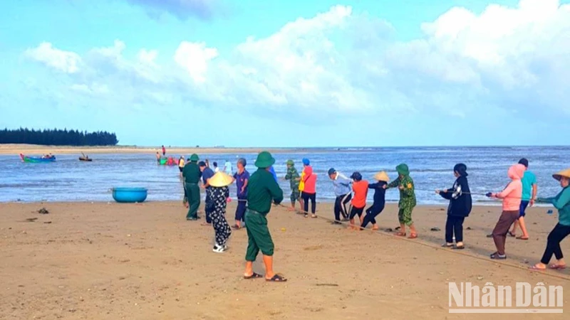 Bộ đội Biên phòng và người dân hỗ trợ anh Phạm Thanh Huân kéo thuyền đánh cá bị nạn vào bờ. 