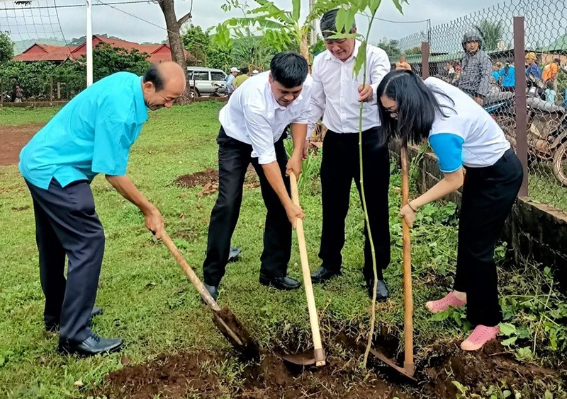 Các đại biểu tham gia trồng cây trong khuôn viên nhà rông làng Kép 1.