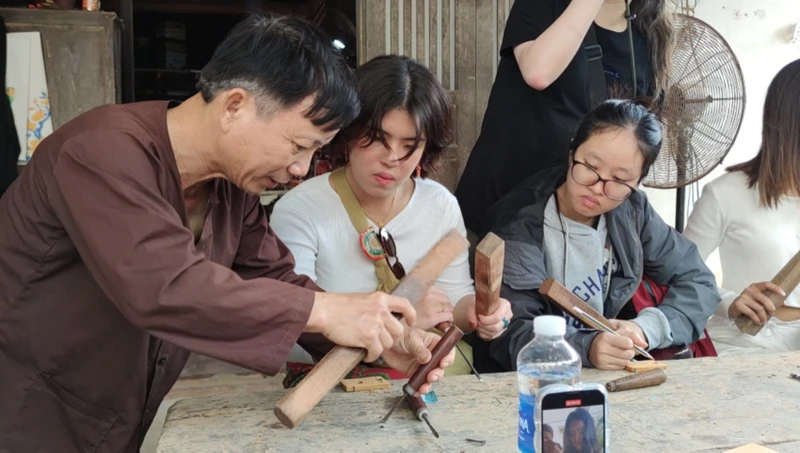 Nghệ nhân Ưu tú Huỳnh Sướng hướng dẫn các bạn sinh viên Hồng Công (Trung Quốc) trải nghiệm nghề mộc.