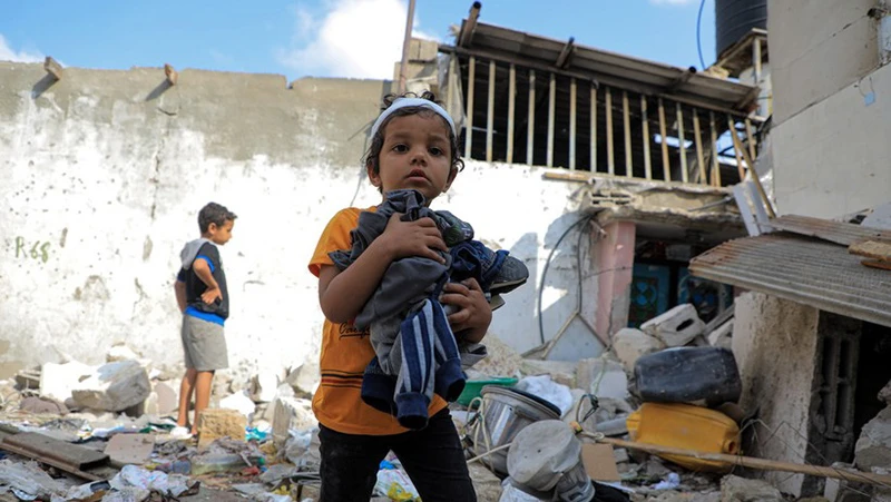 Các em nhỏ thu nhặt đồ đạc sót lại trong đống đổ nát của ngôi nhà bị phá hủy sau cuộc tấn công của Israel vào thành phố Rafah, Dải Gaza ngày 1/5/2024. (Ảnh: THX/TTXVN)