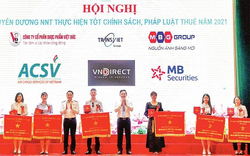 Lãnh đạo thành phố Hà Nội và Cục Thuế Hà Nội trao Cờ thi đua và Bằng khen của UBND thành phố cho các doanh nghiệp nộp thuế tiêu biểu. (Ảnh NHA TRANG) 