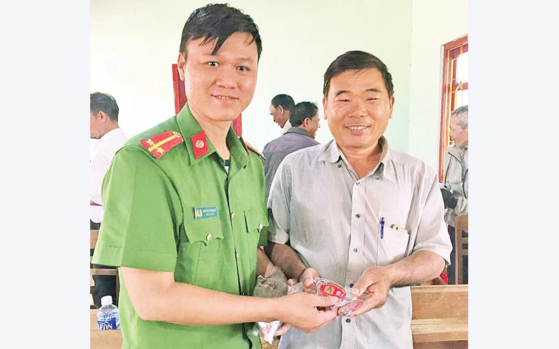 Cán bộ Công an xã Ia Băng (huyện Ðắk Ðoa, Gia Lai) trao móc khóa cho người dân. 