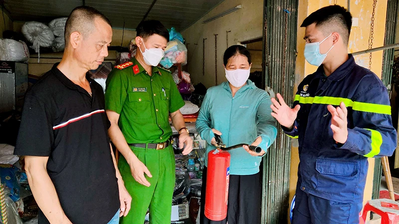 Cán bộ Cảnh sát PCCC và CNCH Công an huyện Thanh Trì, TP Hà Nội hướng dẫn tiểu thương chợ Yên Mỹ, huyện Thanh Trì sử dụng bình chữa cháy. (Ảnh HUY HOÀNG) 