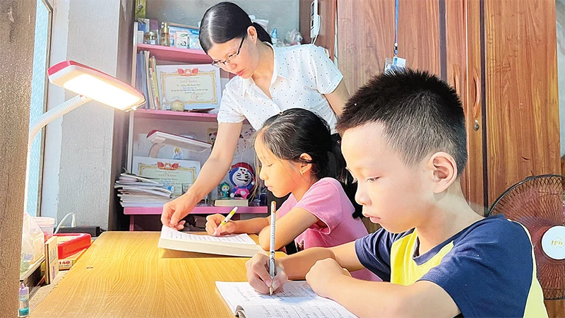 Mẹ đỡ đầu (Hội Phụ nữ phường An Phụ, thị xã Kinh Môn) hướng dẫn hai chị em Lương Thị Thanh Hiền và Lương Việt Hoàng làm bài tập. 