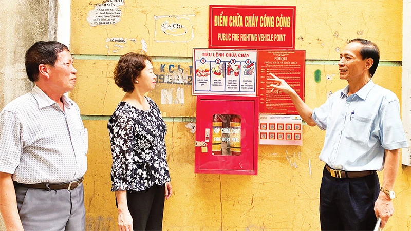 Ông Trương Ðình Quý (bên phải), Bí thư Chi bộ kiêm Trưởng ban Công tác Mặt trận Tổ dân phố số 5, phường Trung Văn hướng dẫn người dân sử dụng phương tiện chữa cháy. 