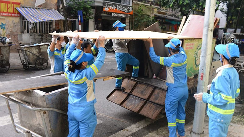 Công nhân Công ty TNHH một thành viên Môi trường đô thị Hà Nội dọn vệ sinh trên tuyến phố Triệu Việt Vương. (Ảnh lam vy) 