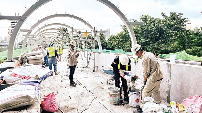 Công nhân thi công cầu bộ hành kết nối với các ga của tuyến Metro số 1 Bến Thành-Suối Tiên. 