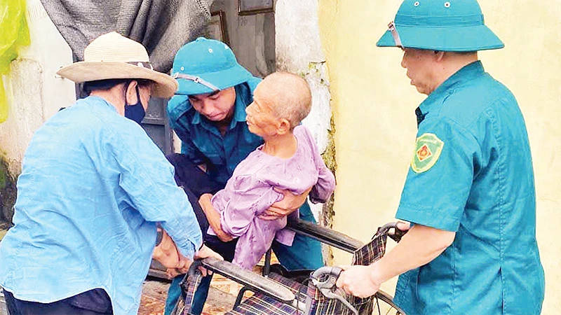 Chính quyền địa phương giúp đỡ những người già yếu, tàn tật sơ tán khỏi mưa lũ. 