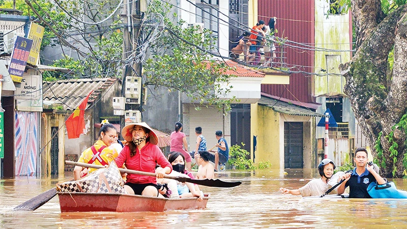 Người dân xã Yên Mỹ, huyện Thanh Trì, Hà Nội được hỗ trợ di chuyển đến nơi an toàn khi nước dâng cao. (Ảnh THẾ ÐẠI) 