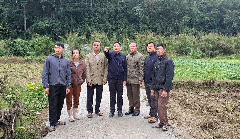 Ông Nông Văn Hòa (đứng giữa) giới thiệu với người dân về hiệu quả bê-tông hóa đường giao thông nông thôn.