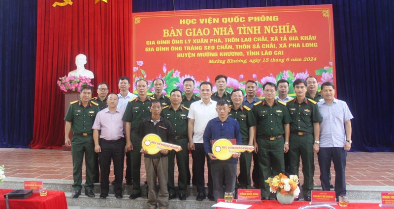 Các đại biểu chụp ảnh lưu niệm cùng 2 gia đình được nhận bàn giao “Nhà tình nghĩa”.