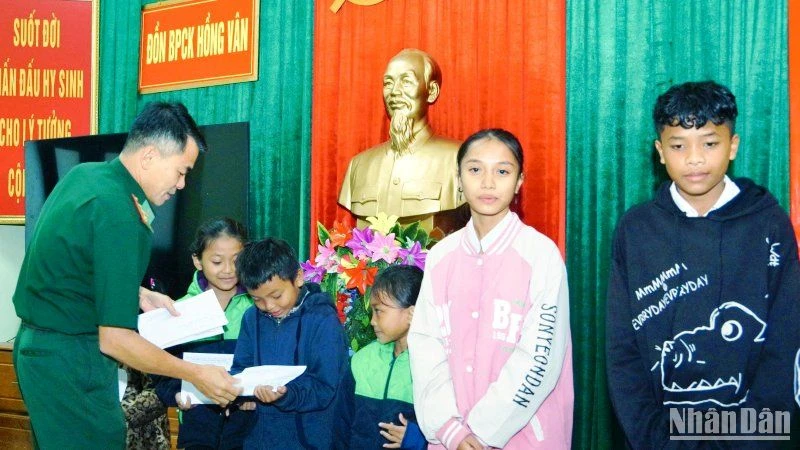 Đại diện Đồn Biên phòng Cửa khẩu Hồng Vân trao kinh phí hỗ trợ cho các em học sinh. (Ảnh: Võ Tiến).