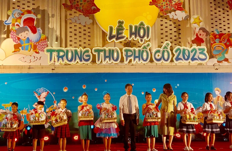 Lãnh đạo Uỷ ban nhân dân quận Hoàn Kiếm trao quà cho các em học sinh.