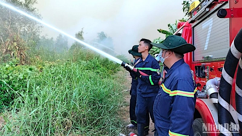 Lực lượng chức năng tiếp tục phun nước dập cháy ngún tại Nông trường 402 vào sáng 11/4.