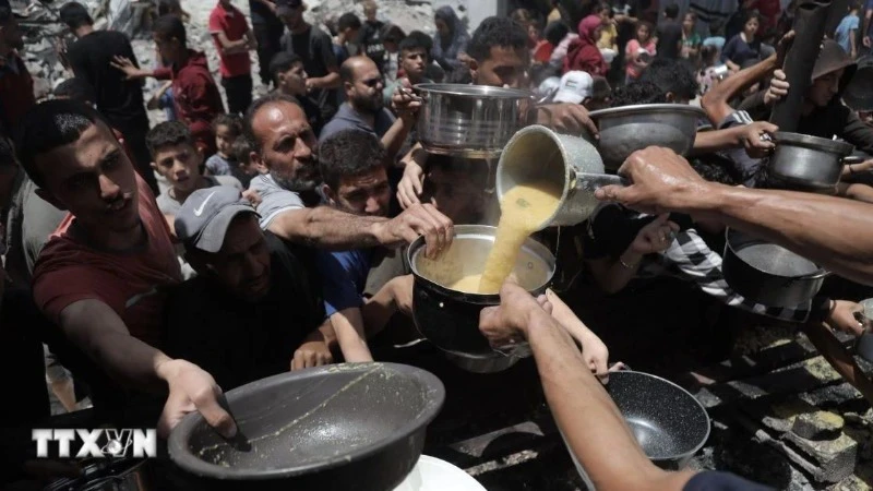 Người dân Palestine nhận thức ăn cứu trợ tại trại tị nạn Jabalia, miền bắc Dải Gaza ngày 19/5. (Ảnh: THX/TTXVN)
