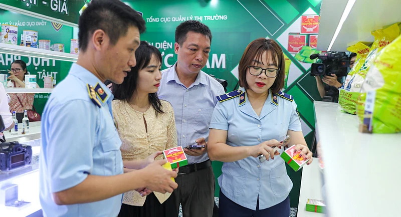 Chuyên viên của Tổng cục Quản lý thị trường hướng dẫn khách tham quan nhận diện bánh cốm Nguyên Ninh thật - giả. (Ảnh: NAM NGUYỄN)