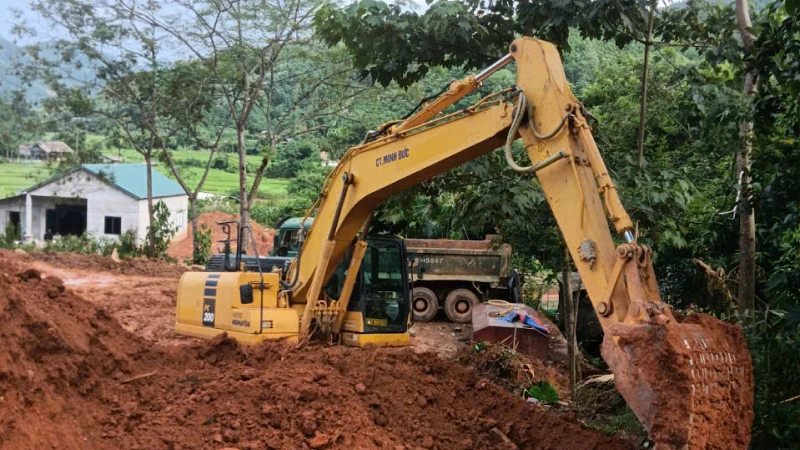 Phương tiện xe máy san lấp mặt bằng chuẩn bị khởi công dự án Khu tái định cư Làng Nủ.