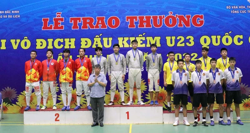 Ban tổ chức trao huy chương cho các vận động viên nội dung đồng đội nam kiếm chém.