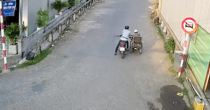 Trần Thanh Vũ (ngồi mô-tô) giả vờ hỏi mua rồi cướp 96 tờ vé số của ông Nguyễn Văn Vĩnh đang ngồi xe lăn. (Ảnh từ camera an ninh).