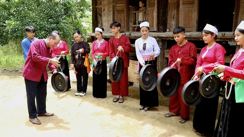 Nghệ nhân ưu tú Bùi Thanh Bình ( bên trái) hướng dẫn các em học sinh tìm hiểu và đánh Chiêng Mường, CLB Giữ gìn bản sắc văn hóa dân tộc Mường, trường THPT Quyết Thắng, Lạc Sơn – Hòa Bình.