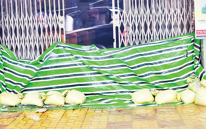 Người dân dùng bạt ni-lông, bao cát ngăn nước tràn vào nhà. 