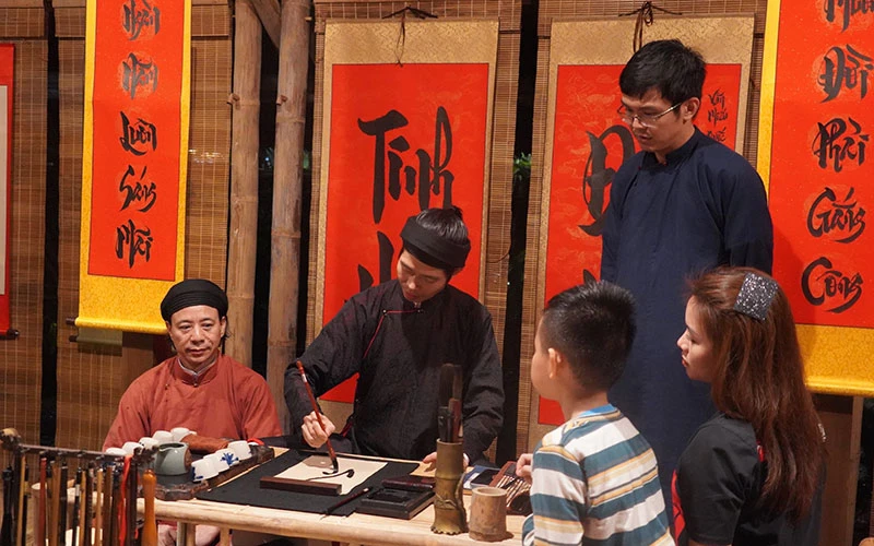 Khách du lịch xin chữ khi tham gia tour đêm tại Văn Miếu - Quốc Tử Giám.