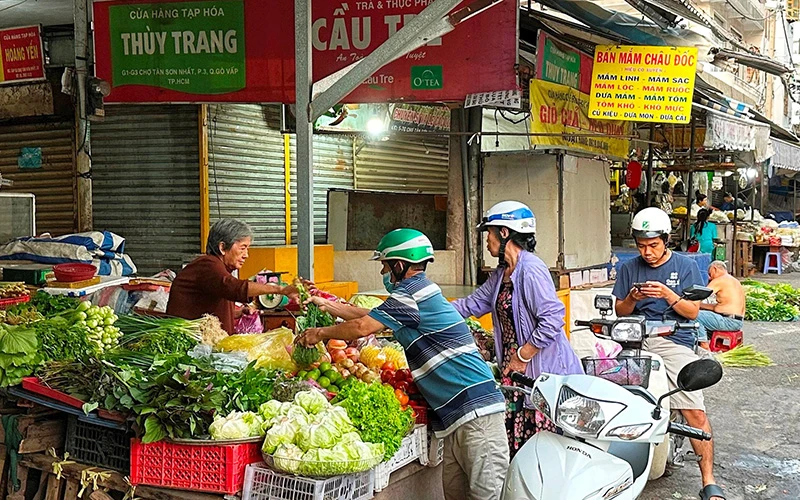 Người dân mua rau quả tại chợ Tân Sơn Nhất trong sáng mồng 4 tháng Giêng. (Ảnh HOÀNG LIÊM)