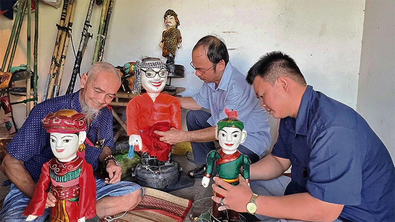 Nghệ nhân Tiến Hòa (trái) cùng các diễn viên trong đoàn chỉnh sửa con rối trước khi biểu diễn.