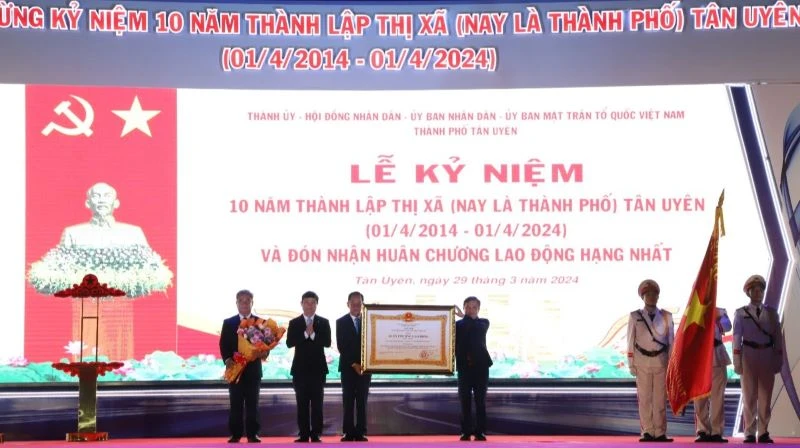 Thừa ủy nhiệm, Chủ tịch Ủy ban nhân dân tỉnh Bình Dương Võ Văn Minh (thứ 2 từ trái sang) trao Huân chương Lao động hạng Nhất cho lãnh đạo thành phố Tân Uyên. 