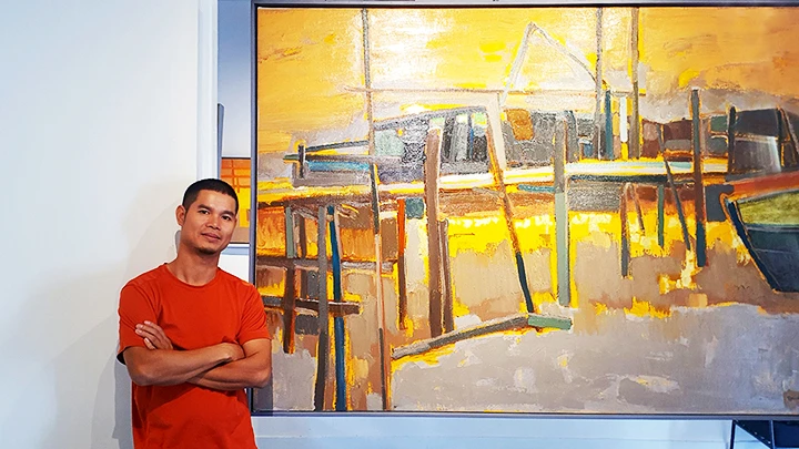 Họa sĩ Đặng Hữu bên tác phẩm của anh tại “Dấu người đi”.