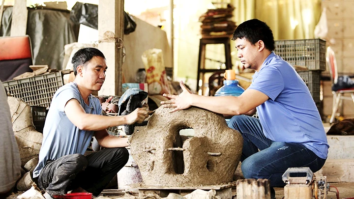 Anh Nguyễn Văn Huỳnh (bên phải) cùng thợ hoàn thiện khuôn đúc đồng.