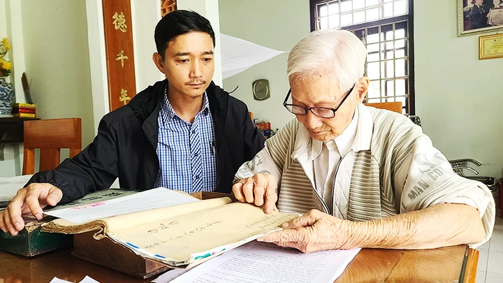 Cụ Hà Thúc Duyên lần dở cuốn địa bạ thời Vua Gia Long. 