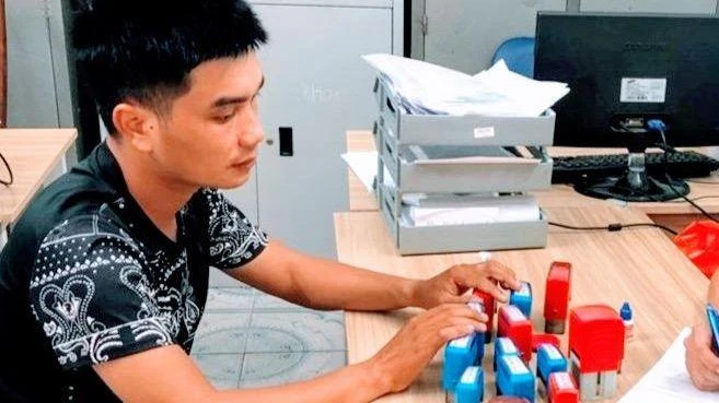 Đối tượng Phạm Đình Hậu cùng số con dấu giả bị thu giữ.