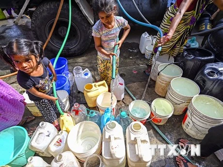 Các em nhỏ hứng nước sinh hoạt dưới trời nắng nóng tại New Delhi, Ấn Độ, ngày 22/5/2023. (Ảnh: AFP/TTXVN)