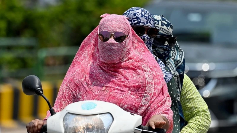 Người dân trùm kín tránh nắng nóng khi di chuyển tại Raipur, Ấn Độ. (Ảnh: AFP/TTXVN)